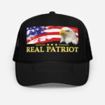 Front of Real Patriot USA Flag Eagle black foam trucker hat showing printed flag and eagle design. Real Patriot in gold-colored font.