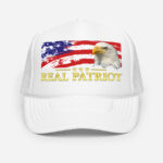 Front of Real Patriot USA Flag Eagle white trucker hat showing printed flag and eagle design. Real Patriot in gold-colored font